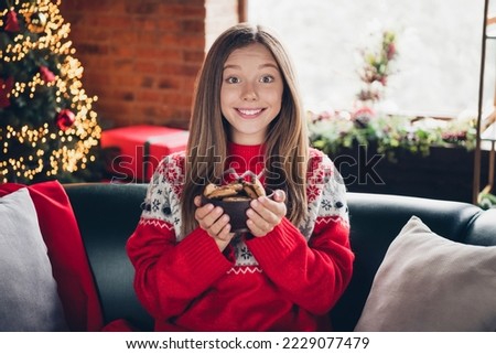 Portrait of funny positive girl hands hold chocolate cookies bows toothy smile enjoy newyear fairy indoors