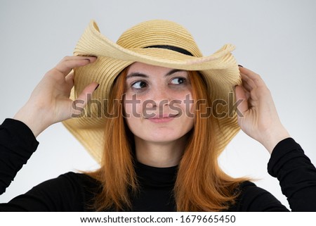 Portrait of funny redhead woman in bag yellow straw hat.