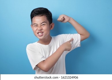 Portrait Of Funny Strong Healthy Asian Boy Shows His Muscle And Strength, Confident Kid Shows His Biceps Arm Muscle