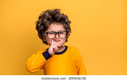 Portrait of funny thinking kid in glasses isolated on yellow background. Five years old smart boy with finger near mouth. Ask questions. Critical thinking. Back to school - Shutterstock ID 2090546728