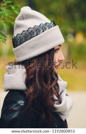 Portrait of funny young girl in the autumn weather in warm clothes and hat.