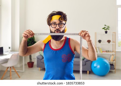 Portrait Of Funny Young Man Demonstrating Amazing Weight Loss Result After Regular Sport Workouts. Fitness Instructor Holding Measuring Tape Motivating You To Exercise And Lose Weight Quickly