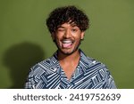 Portrait of funny young positive american man in shirt stick tongue out humorous comic joking blink eye isolated on khaki color background