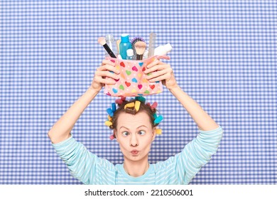 Portrait Of Funny Young Woman With Colorful Hair Curlers On Head, Holding Makeup Bag With Beauty Treatment Accessories And Cosmetics, Making Goofy Face, Fooling Arounds Over Shower Curtain Background