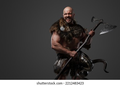 Portrait Of Furious Nordic Warrior With Muscular Build Dressed In Armor Holding Axe.