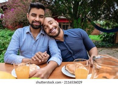 Portrait Of Gay Couple Smiling And Holding Hands Outside In The Garden