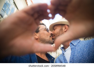 Portrait Of Gay Men Kissing. Mid Adult Man In Casual Clothes Showing Affection, Making Heart Sign With Hands. Love, Affection, Relationship Concept