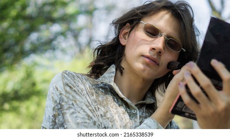 Portrait Of A Gay Person Applying Makeup In A Park.