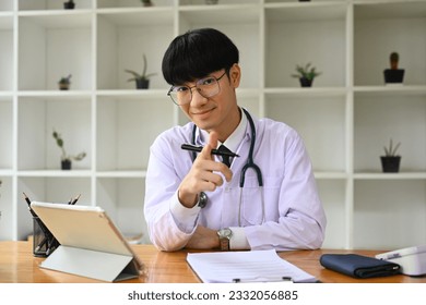Portrait of general practitioner doctor in white uniform sitting in modern workplace and smiling to camera - Shutterstock ID 2332056885