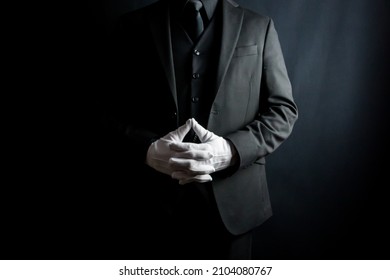 Portrait of Gentleman in Dark Suit and White Gloves Standing on Black Background. Professional Service and Professional Hospitality.