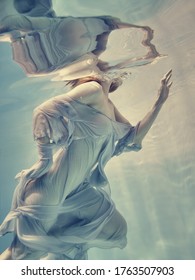       Portrait of a girl in a blue dress floating underwater                         