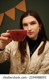 Portrait Of A Girl In A Cafe In A White Sweater On A Green Background Holding Red Mug