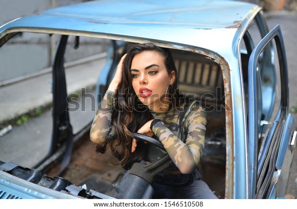 portrait of girl in camouflage print blouse\
and jean pants near the old car in the\
street