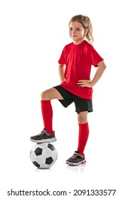Portrait of girl, child, football player in red uniform training, posing isolated over white background. Concept of action, sportive lifestyle, team game, health, energy, vitality. Copy space for ad