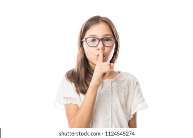 Portrait of girl child keeping finger on her lips and asking to keep quiet, isolated over white background