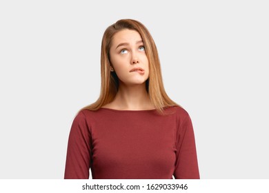 Portrait girl confused frightened look bite lip. Beautiful young woman wears Burgundy-colored jacket sleeves isolated on white background in Studio with an empty space for text and advertising. - Shutterstock ID 1629033946