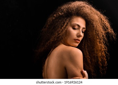 Portrait of a girl with curly lush hair, with a bare back and shoulder photo in color. Minimalism and naturalness. Light colors.
