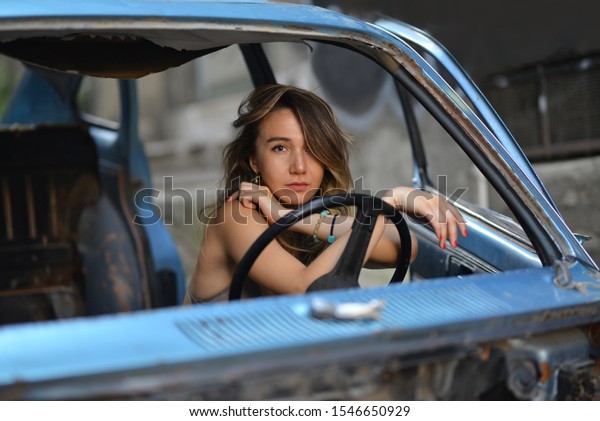 portrait of girl in green bra,\
camouflage print pants and necklace near the blue old car in the\
street