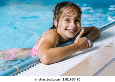 Portrait Girl Having Fun In Indoor Swimming-pool. The Girl Is Resting At The Water Park. Active Happy Kid. Swimming School For Small Children. Concept Friendly Family Sport And Summer Vacation.