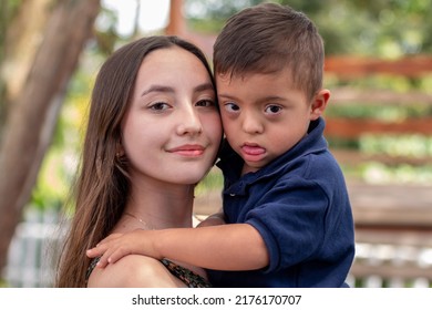 Portrait Of A Girl Holding Her Brother With Down Syndrome. Disability, Inclusion And Diversity.