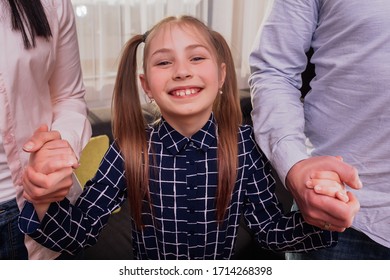 portrait of a girl holding her parents hands. The girl smiles and feels the support of her parents.
