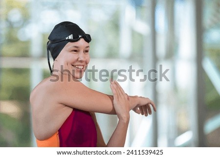 Portrait of a girl at the indoor pool, a female swimmer with swimming goggles, smiling