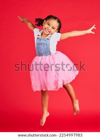Portrait, girl and jumping in tutu skirt on red background, studio and fun fashion. Happy kid, ballet clothes and energy for performance, dance and smile with happiness, ballerina dress and princess