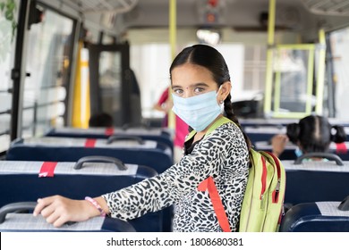 Portrait Of Girl Kid Student In Medical Mask Inside The School Bus Looking At Camera - Concept Of School Reopen Or Back To School With New Normal Lifestyle.