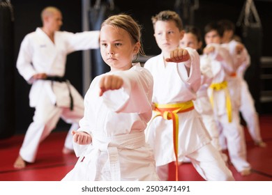 Portrait of girl kid training karate movements in sport class in school