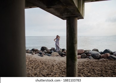 portrait girl in long dress near the pier by the sea
