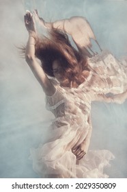          Portrait of a girl with long hair and in a lace dress underwater on a light background                      