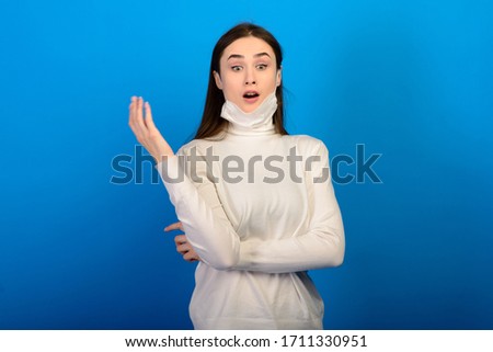 Portrait of a girl in a medical mask, which puts on a rubber glove. Blue background. Copy space.