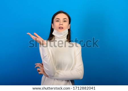 Portrait of a girl in a medical mask, which puts on a rubber glove. Blue background. Copy space.