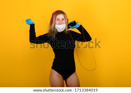 Portrait of a girl in a medical mask, which puts on a rubber glove. Yellow and grey background. Copy space.