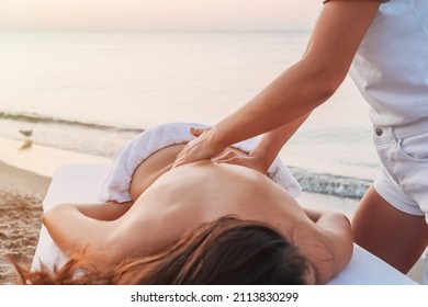 Portrait of girl on massage table by sea getting back massage. Masseur at work at resort. Vacation massage services