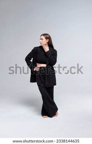 Portrait of a girl on a white background in a classic black suit. Studio shooting vertical photo. 