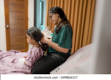 Portrait Of Girl Patient And Mother Comb Hair In Hospital Childrens Ward.