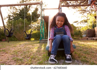 Portrait Of Girl Playing Outdoors At Home On Garden Slide