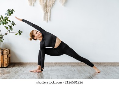 Portrait of a girl practicing yoga in a black suit.One of the main poses in yoga, the pose of a warrior.Virasana.Zen.Development of rolling stock and ankles. High quality photo