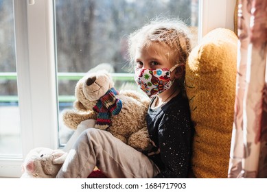 Portrait Of A Girl In A Protective Mask . A Sick Child Wearing A Protective Mask. Patient Isolated In House To Prevent Infection. Coronavirus. Teaching Your Child Preventive Measures Against Covid-19