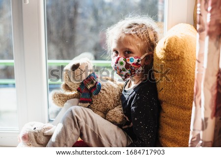Portrait of a girl in a protective mask . A sick child wearing a protective mask. Patient isolated in house to prevent infection. Coronavirus. Teaching your child preventive measures against covid-19