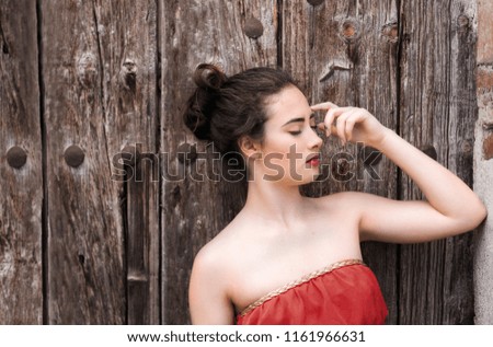 Portrait of a girl in red dress on a wooden door