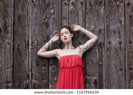 Portrait of a girl in red dress on a wooden door