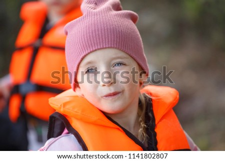 Portrait of a girl in a red life jacket.