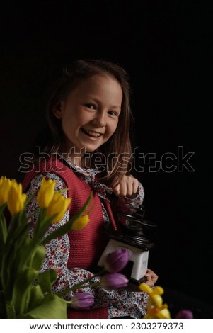 Portrait of a girl in rural clothes and a retro coffee grinder in her hands on a dark background. Medieval little girl