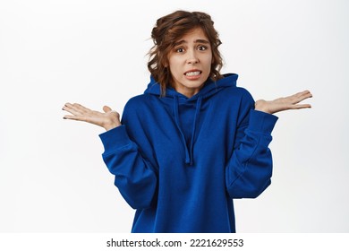 Portrait Of Girl Shrugging With Guilty, Awkward Face, Apologizing For Not Knowing, Being Clueless, Standing Over White Background