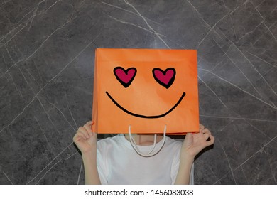 Portrait of a girl with smiley heart eyes on shopping bag with Dark background text space  - Mental Emotion and Feeling Concept 