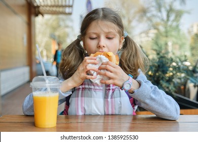 Portrait Of Girl Student With Backpack, Eating Burger With Orange Juice, Background Of Outdoor Fast Food Cafe.