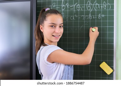 Portrait Of Girl Student Of Teenager 13 Years Old At School Near Chalk Board. Schoolgirl In Classroom At Math Lesson