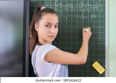 Portrait Of Girl Student Of Teenager 13 Years Old At School Near Chalk Board. Schoolgirl In Classroom At Math Lesson